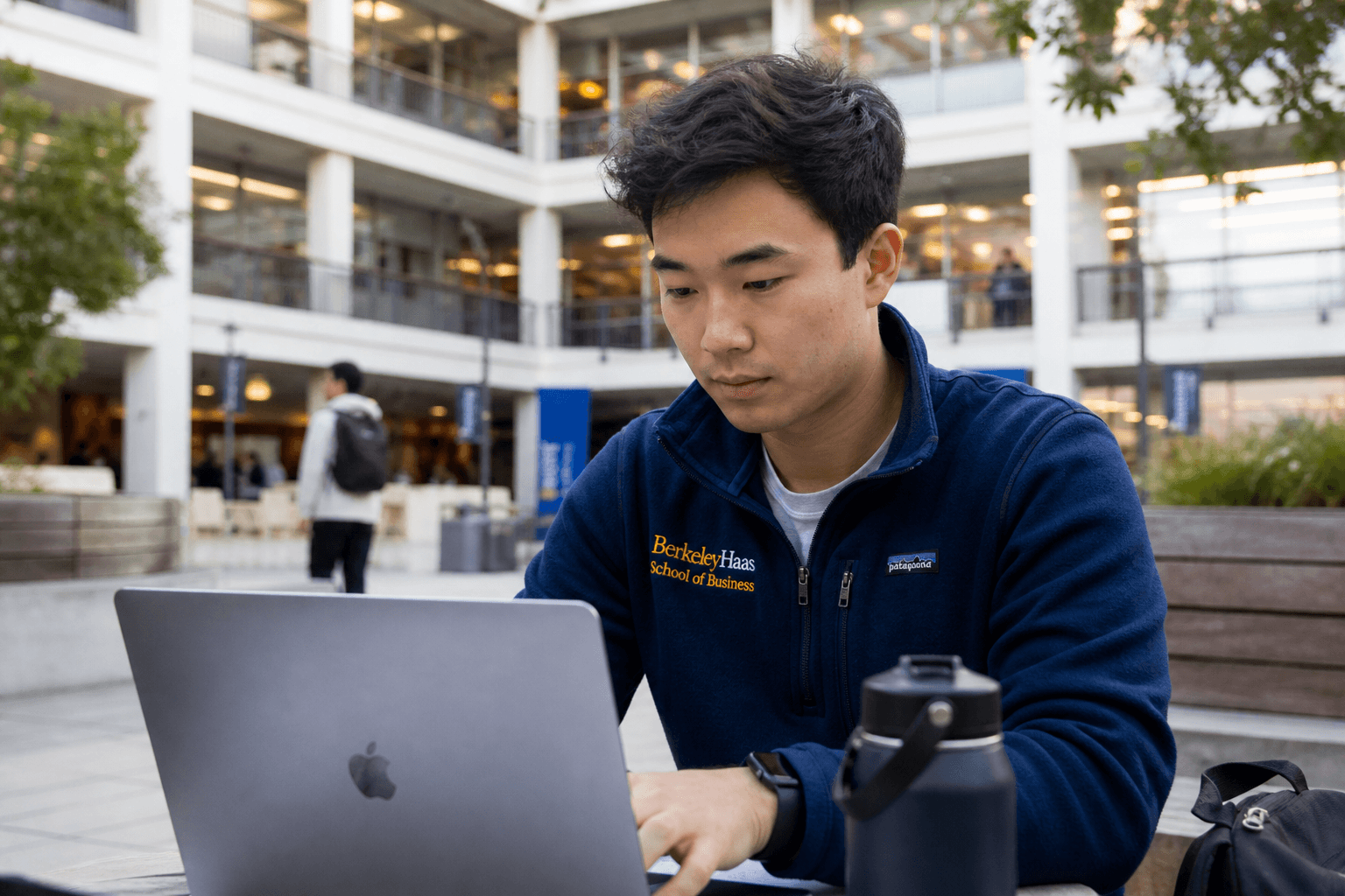 A Berkeley Haas MBA student working on a laptop in the Haas courtyard.